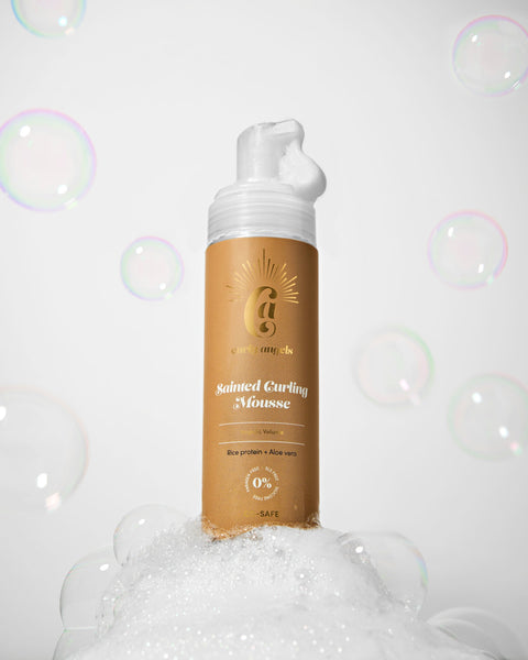 Curly Angels Sainted Curling Mousse against golden fabric backdrop Curly Angels Sainted Curling Mousse against golden fabric backdrop