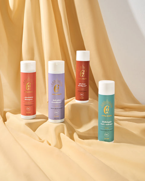 Curly Angels Collection Set Against of Four Haircare Products against a Golden Fabric Backdrop Showing  Curly Angels Collection Set Against of Four Haircare Products against a Golden Fabric Backdrop Showing