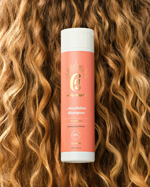A bottle of vegan Absolution Shampoo by Curly Angels resting on wavy red hair, formulated to gently and effectively cleanse all curly hair types - sulphate-free and  paraben-free A bottle of vegan Absolution Shampoo by Curly Angels resting on wavy red hair, formulated to gently and effectively cleanse all curly hair types - sulphate-free and  paraben-free