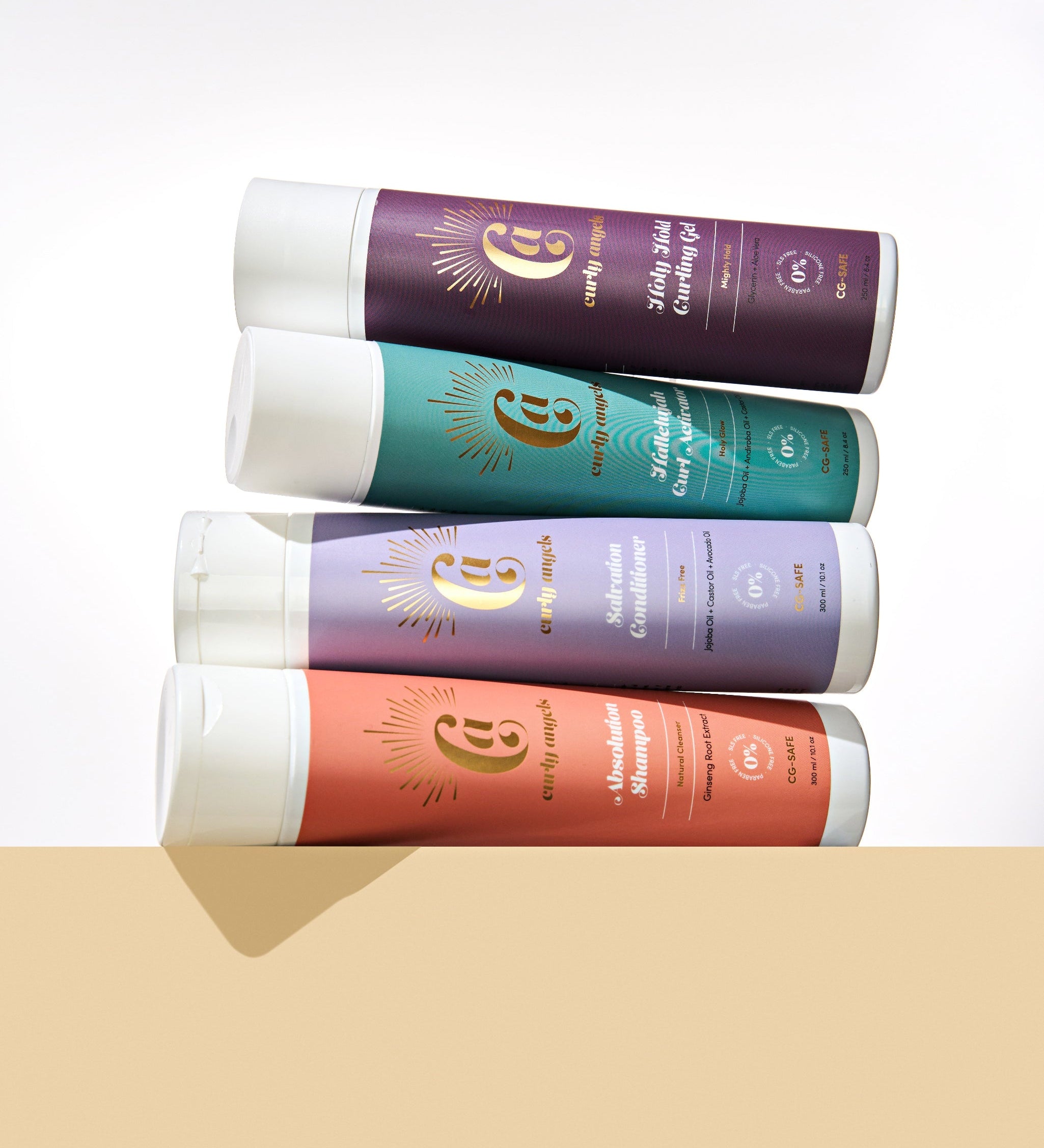 CURLY ANGELS strong hold set absolution shampoo salvation conditioner hallelujah curl activator holy hold curling gel bottles stacked on a biege platform -vegan -cruelty-free -organic