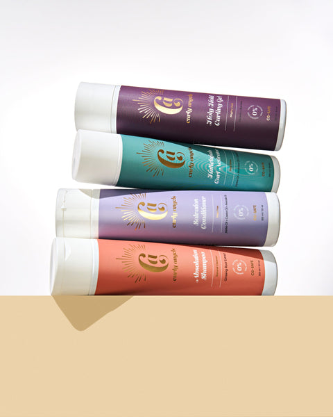 CURLY ANGELS strong hold set absolution shampoo salvation conditioner hallelujah curl activator holy hold curling gel bottles stacked on a biege platform -vegan -cruelty-free -organic