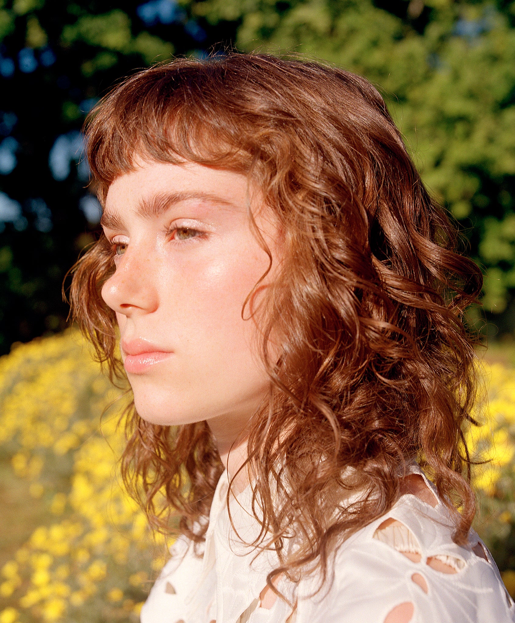 Curly Angels woman with wavy hair in a natural setting with greenery and yellow flowers