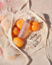 curly angels sacred scent hair mist resting agaainst a cotton bag of mandarins on a beach with scattered freshwater pearl jewellery - vegan - cruelty-free - curly girl method safe