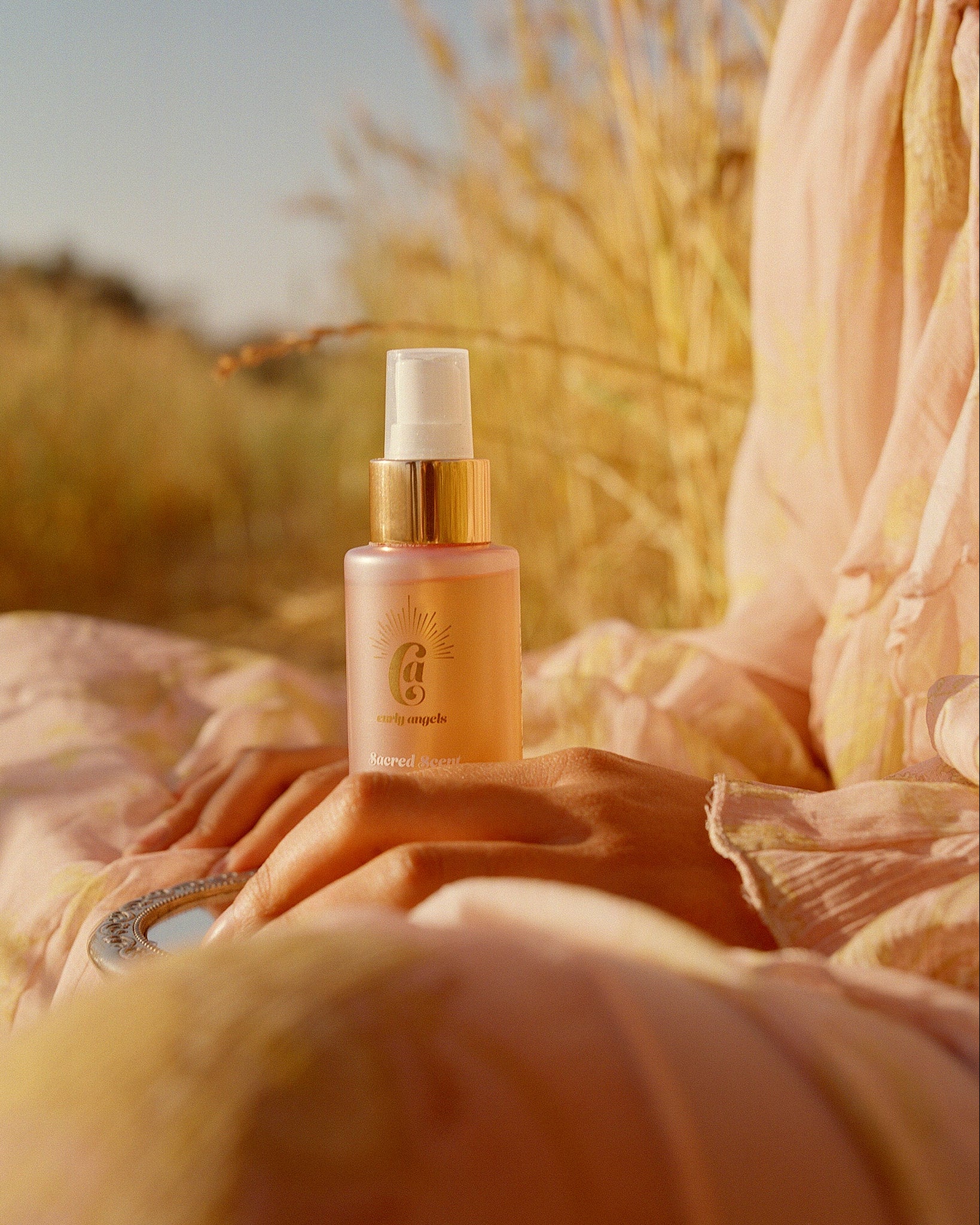 Curly Angels Sacred Scent in golden light resting on the lap of a person sitting in a wheat field - vegan - cruelty-free