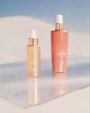 Curly Angels Rejoice Refresh Spray and Sacred Scent Hair Perfume on a mirror set against beach sand and clear blue sky - vegan - cruelty-free - Curly Girl Method Safe 