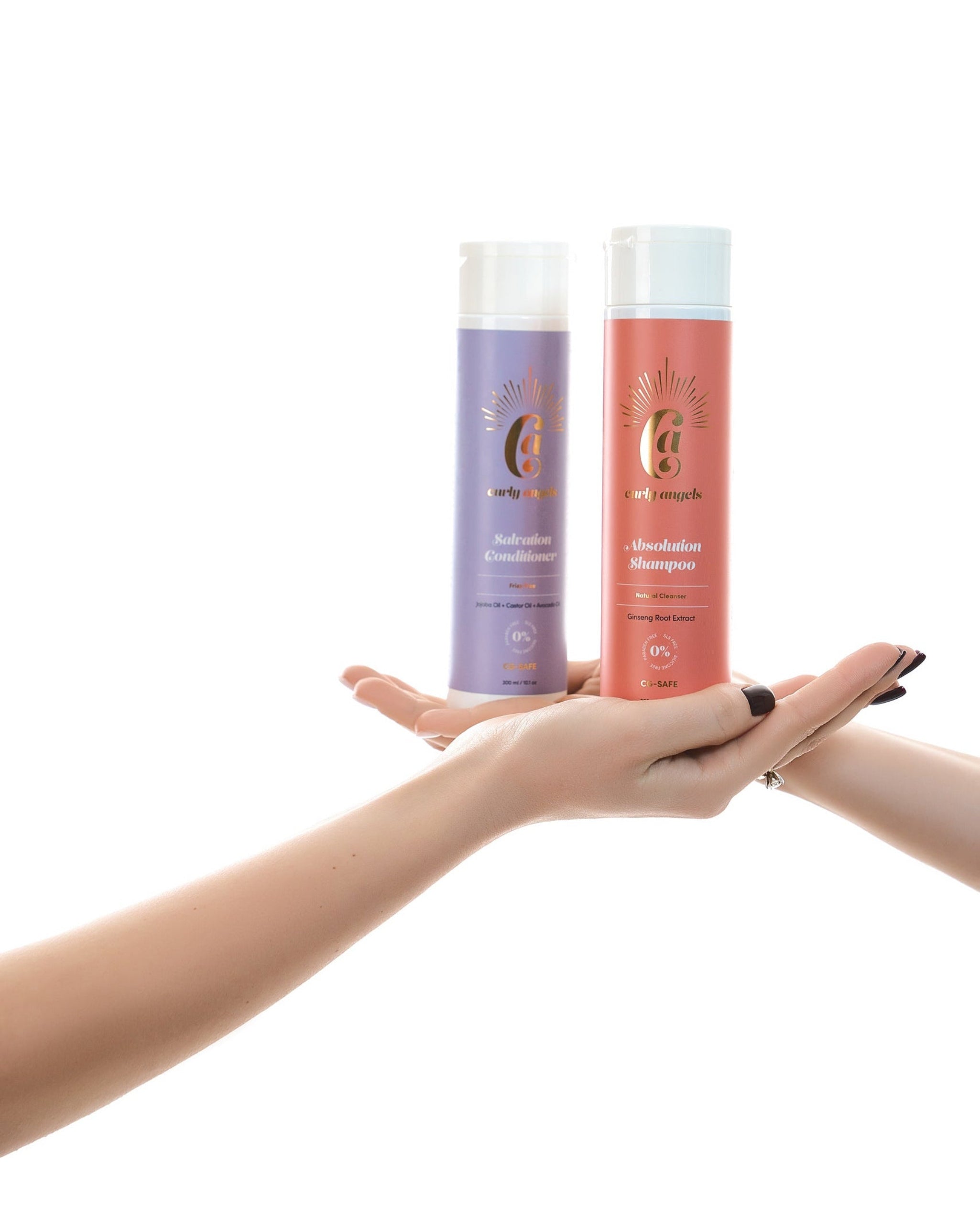 Bottles of Curly Angels Absolution Shampoo and Salvation conditioner being passed between two hands on a white background