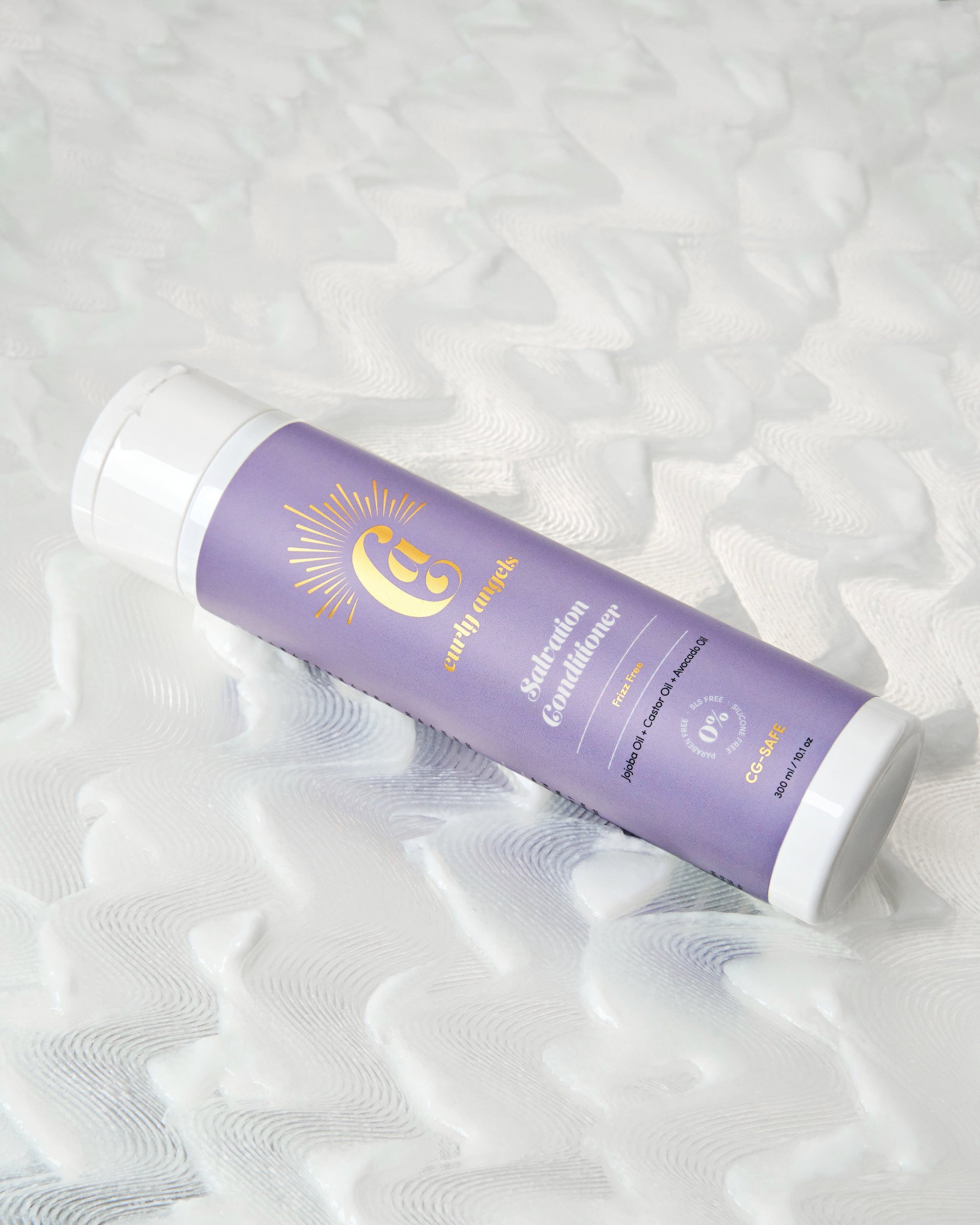 A bottle of Salvation Conditioner by Curly Angel resting on a bed of wavy shampoo designed to deeply nourish and hydrate