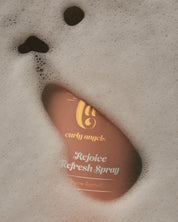 Curly Angels Rejoice Refresh Spray closeup peeking beneath foam