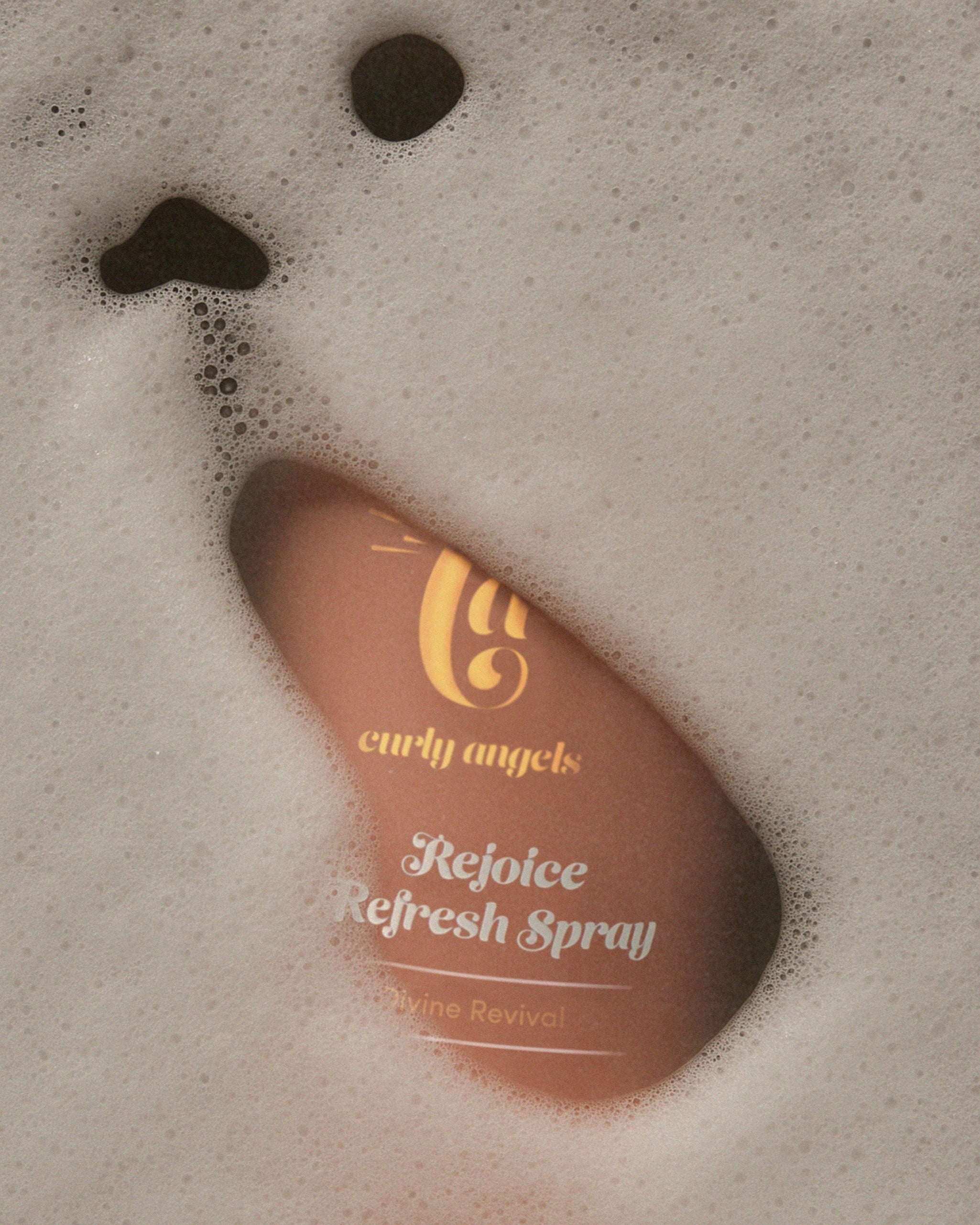Curly Angels Rejoice Refresh Spray closeup peeking beneath foam