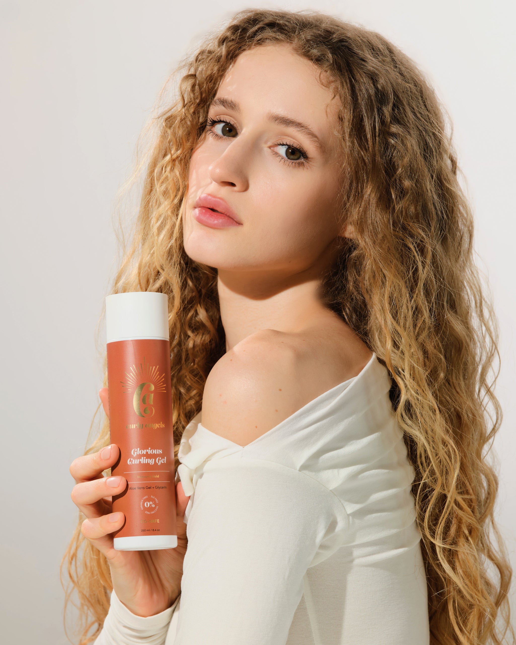 A model holding a bottle of Curly Angels vegan Glorious Curling Gel
