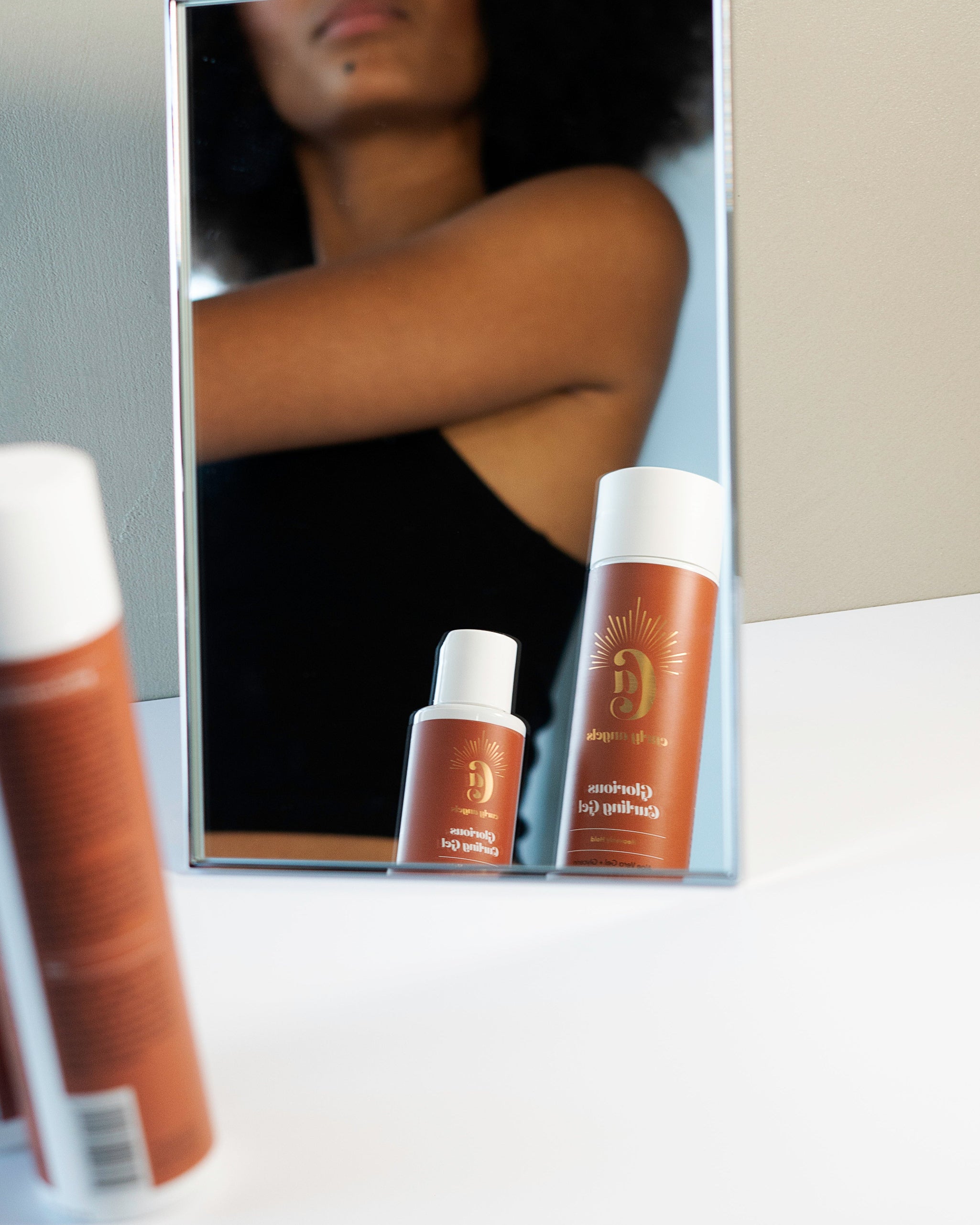 Curly Angels vegan Glorious Curling Gel in front of a mirror reflecting model with afro