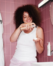 Curly Angels Sainted Curling Mouse Hair Styling 200ml vegan Curly haired model in pink bathroom