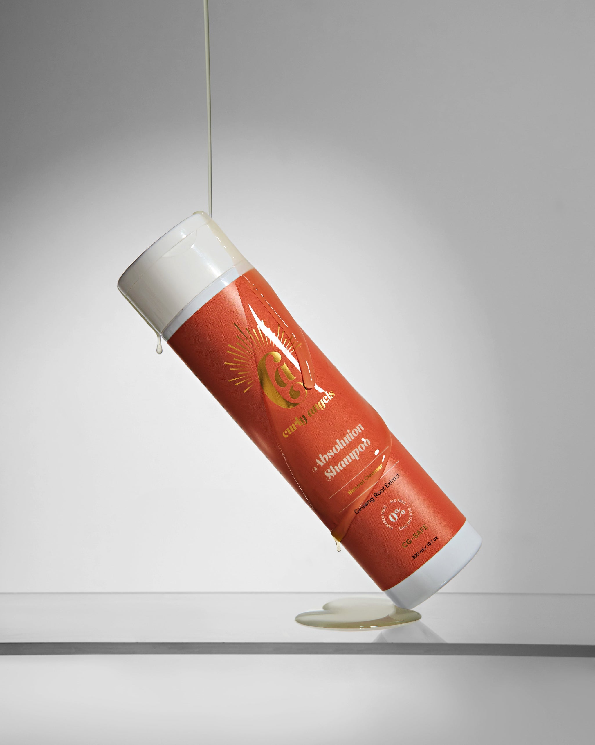 A bottle of vegan Absolution Shampoo by Curly Angels with honey poured onto it -designed to gently and effectively cleanse all curly hair types - sulphates-free and  paraben-free