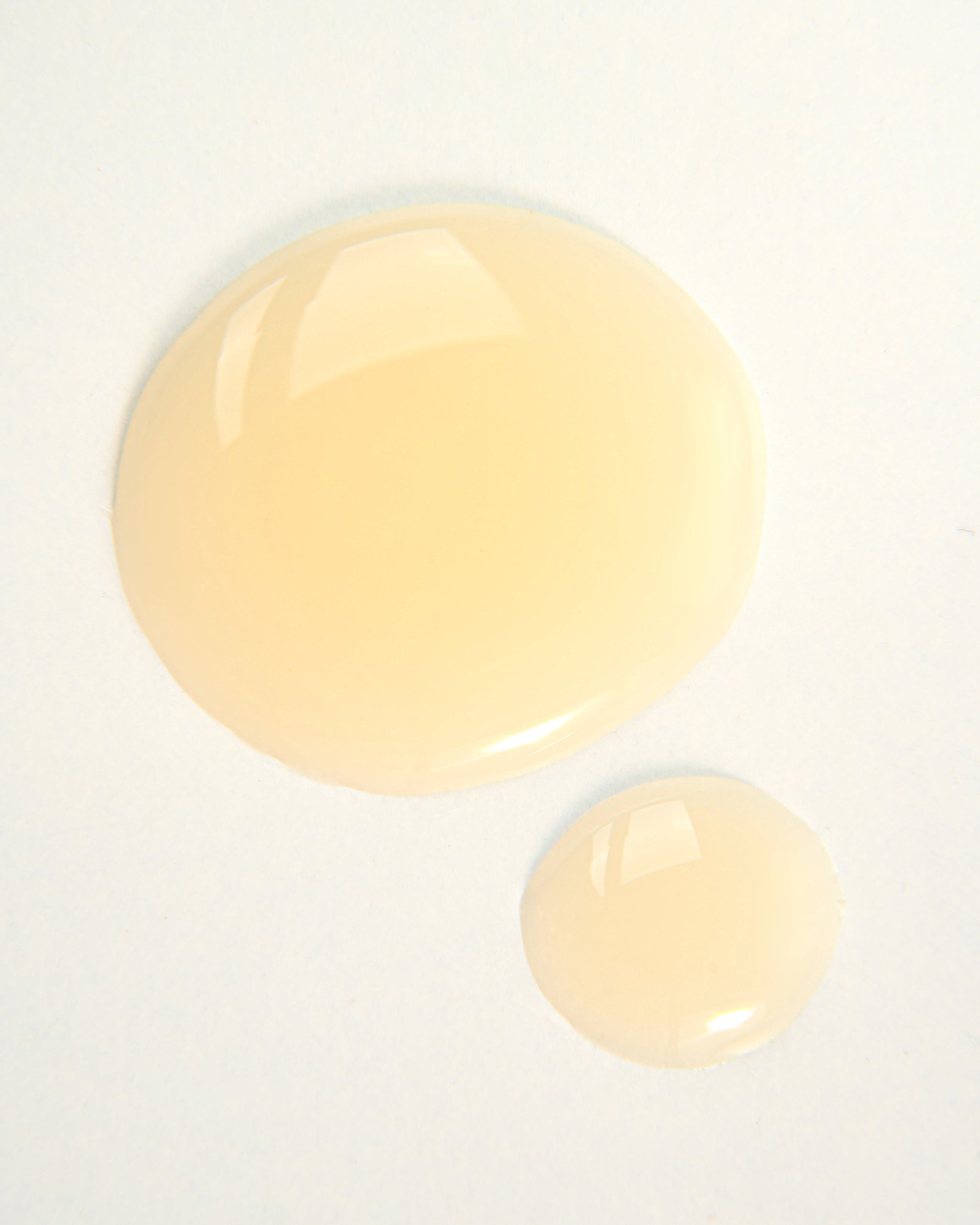 Two droplets of vegan Absolution Shampoo by Curly Angels on a white background 