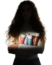 Model in shadow holding the The Curly Angels Collection Set of four bottles including Absolution Shampoo, Salvation Shampoo, Conditioner, Hallelujah Curl Activator, and Glorious Curling Gel. All products are vegan, paraben-free, sulphate free and suitable for all curl types