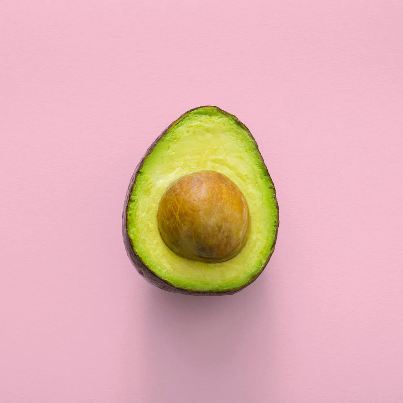 Half-cut avocado on a pink background